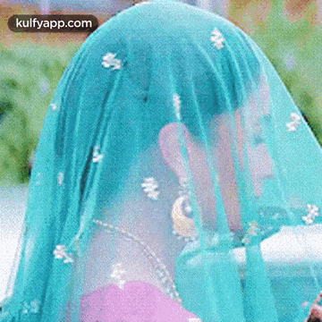 a close up of a woman wearing a blue veil covering her face .