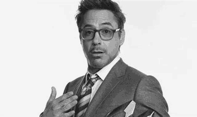 robert downey jr. is wearing a suit and tie and making a surprised face .