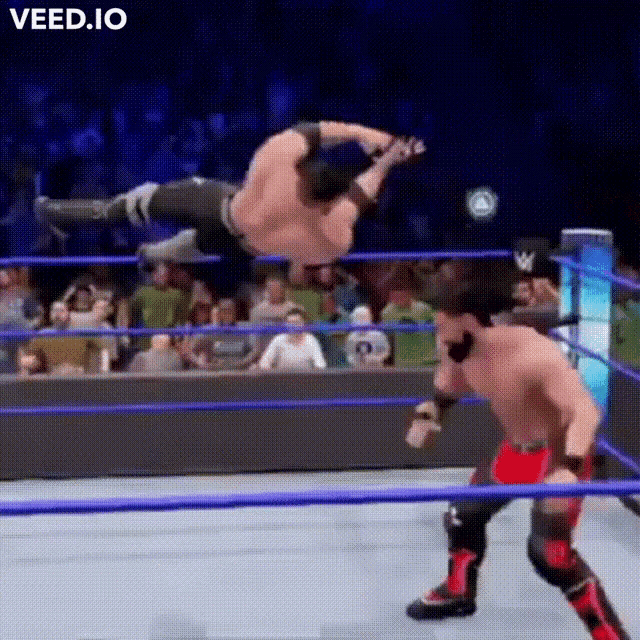 two men are wrestling in a ring and one of them is jumping in the air .