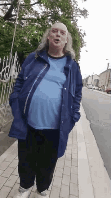 a woman wearing a blue jacket and a blue shirt is walking down a sidewalk