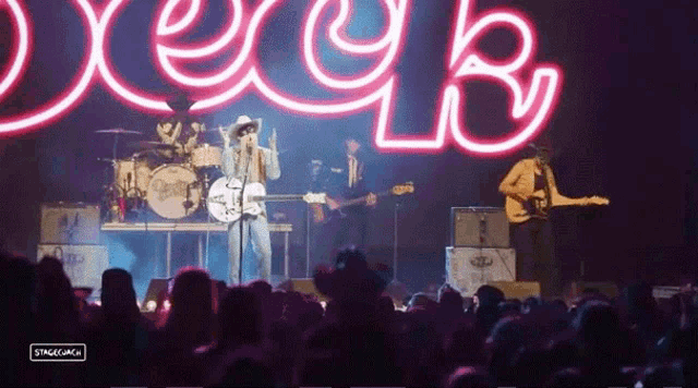 a group of people playing instruments in front of a neon sign that says ' deer ' on it