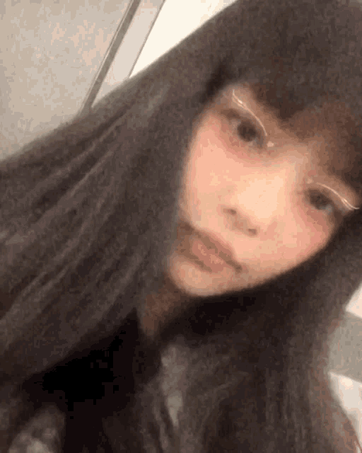 a girl with long black hair is taking a selfie with a hood on .