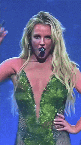 a woman in a green bodysuit is singing into a microphone on stage