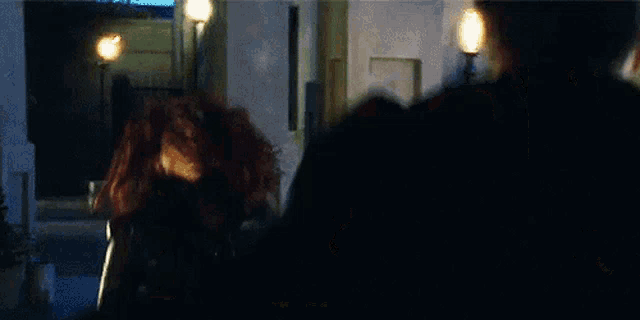 a man and a woman are standing next to each other in a dark room . the woman is wearing a black leather jacket .