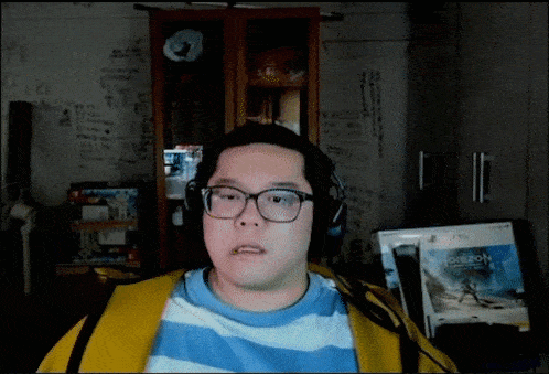 a man wearing headphones and a blue and white striped shirt looks at the camera in front of a horizon game
