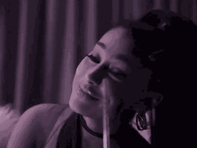 a close up of a woman 's face with a purple background and a straw in her mouth .