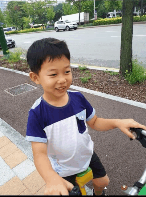 a young boy is riding a bike on a sidewalk and smiling