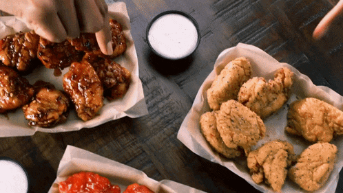 a person is dipping a chicken wing in a bowl of ranch dressing