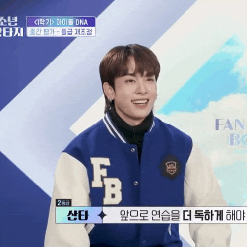 a man wearing a blue and white varsity jacket with the letter fb on the front
