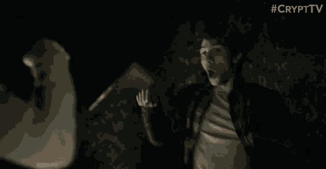 a man is holding a knife in his hand and screaming at another man in a dark room .