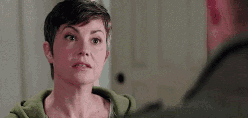 a woman with short hair is looking at a man in a room .