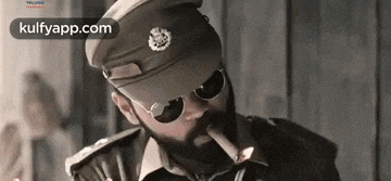 a police officer is smoking a cigar and wearing sunglasses .