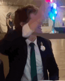 a man in a suit and tie is sitting at a table with his hands on his head .