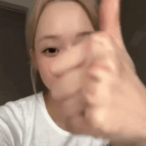 a woman is giving a thumbs up sign with her hand .