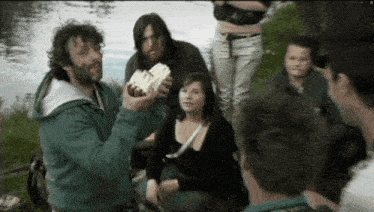 a group of people are gathered around a man holding a piece of food