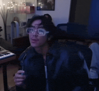 a man wearing glasses and a leather jacket is sitting at a keyboard