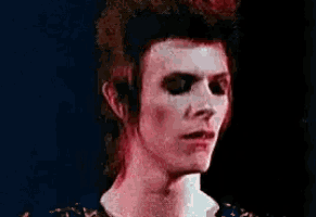 a close up of a man 's face with red hair and a blue shirt .