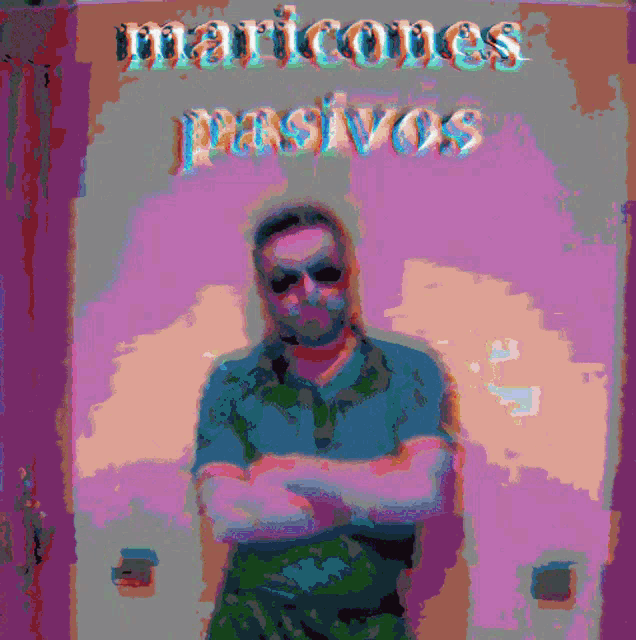 a man with his arms crossed stands in front of a wall with maricones passivos written on it