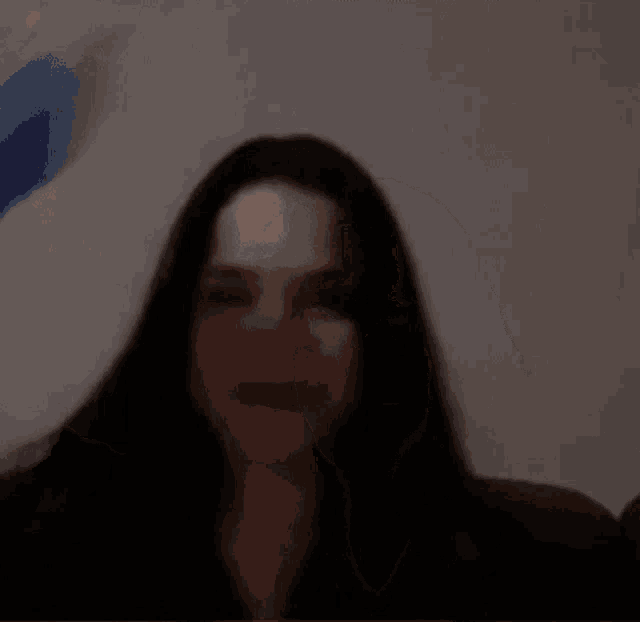 a woman with long black hair is standing in a dark room with her hands in the air .