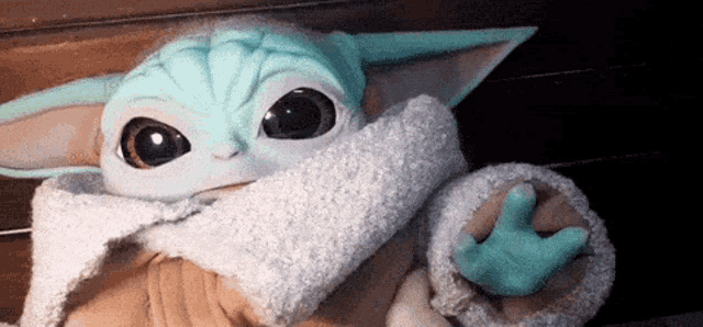 a stuffed animal with big eyes and a scarf around its neck is sitting on a table .