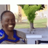 a woman is smiling and talking into a microphone while sitting in front of a window .