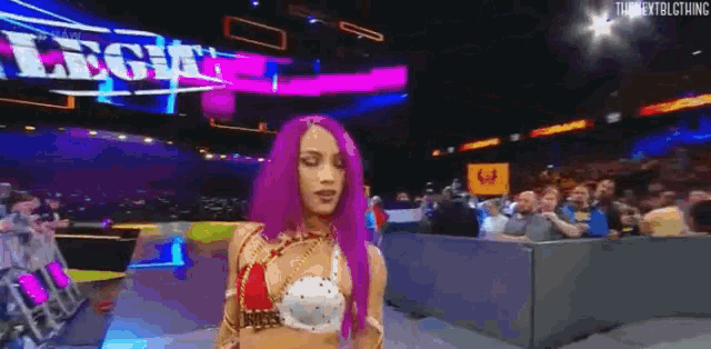 a woman with purple hair is dancing in a wrestling ring .