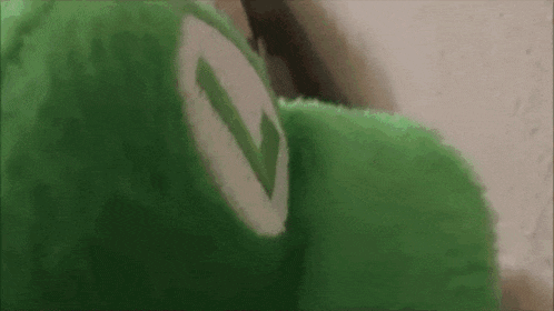 a close up of a green stuffed animal with a white circle on its face .