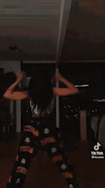 a woman in a white crop top and black shorts is dancing in a living room .