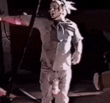 a man in a white shirt and pants is standing on a stage with his pants down .