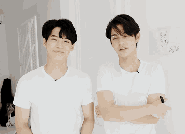 two young men wearing white shirts are standing next to each other smiling