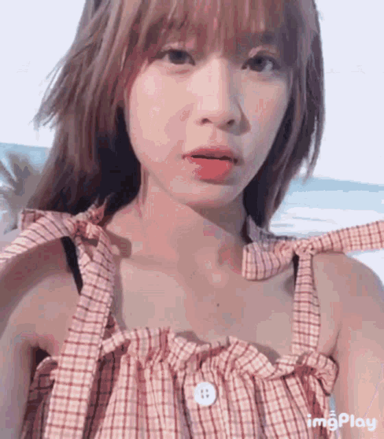 a girl in a plaid dress is taking a selfie with a button on her shirt