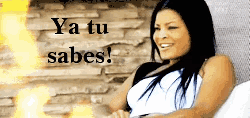 a woman is smiling in front of a brick wall with the words ya tu sabes