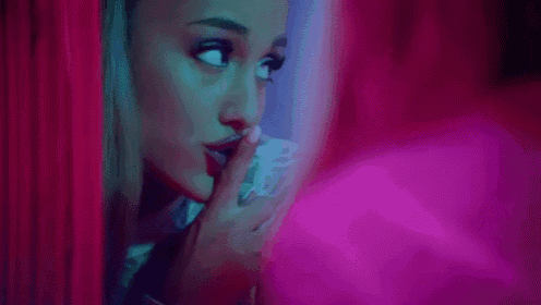 a close up of a woman holding a piece of paper in her hand in a pink room .