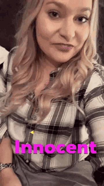 a woman in a plaid shirt is sitting on a couch with the word innocent written on her chest .