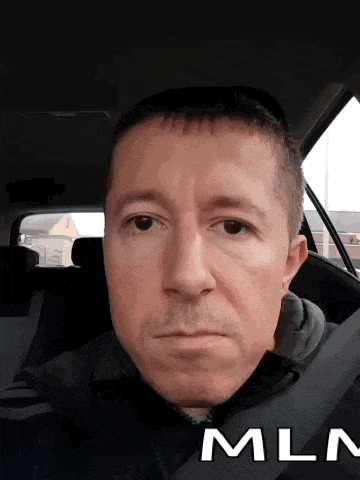 a man sitting in a car with the word mln on the bottom right