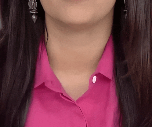 a close up of a woman wearing a pink shirt and silver earrings