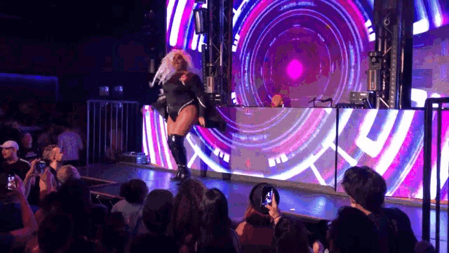 a drag queen performs in front of a crowd at a night club