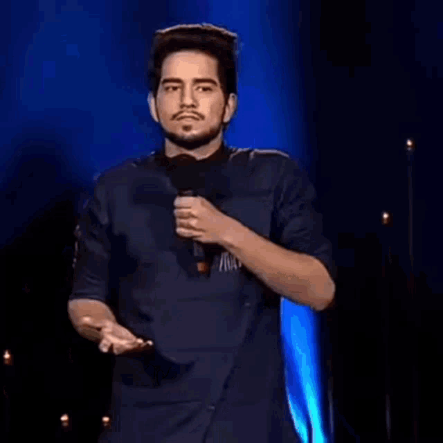 a man is standing on a stage holding a microphone and talking into it .