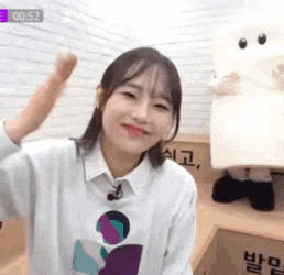 a woman in a white sweater is sitting in front of a box with a stuffed animal behind her .