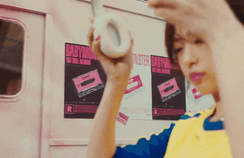 a woman in a yellow shirt is holding a donut in front of a poster that says " babymoon "