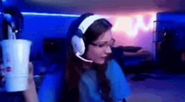 a woman wearing headphones is holding a cup in her hand .