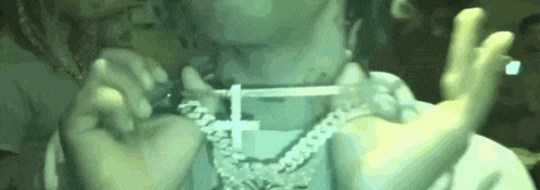a person is wearing a necklace with a cross on it .