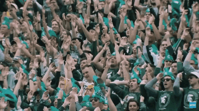 a crowd of people wearing green hats with the word spartans on it