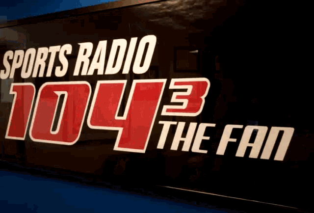 a sign for sports radio 104.3 the fan hanging on a wall