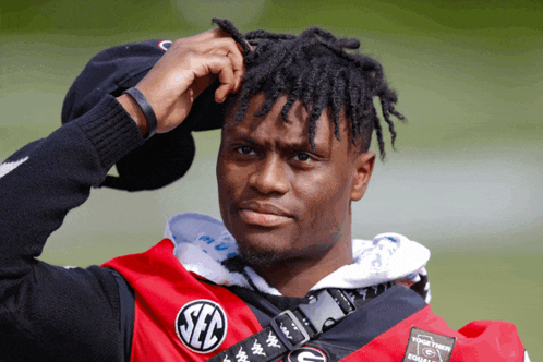 a man with dreadlocks is wearing a red and black shirt that says sec