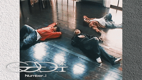 three people laying on a wooden floor with the words number.i written on the bottom