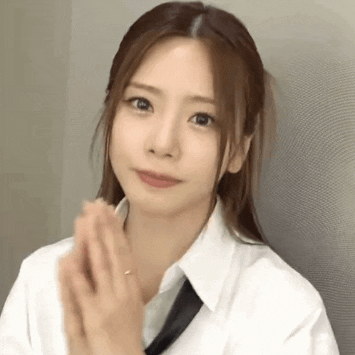 a woman wearing a white shirt and tie is clapping her hands .