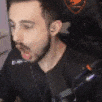 a man with a beard is sitting in a chair with his mouth open and his tongue out .
