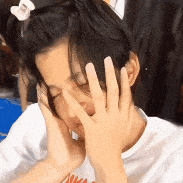 a person covering their face with their hands while wearing a shirt that says nike