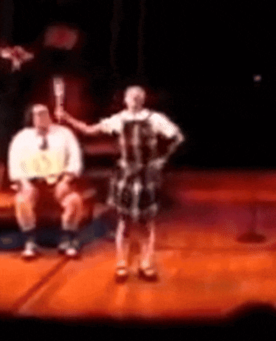 a blurry picture of a man sitting on a couch and a woman dancing on a stage